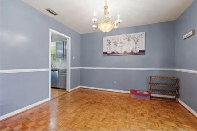 empty room with light parquet flooring and a notable chandelier