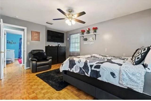 bedroom with connected bathroom, light parquet floors, and ceiling fan