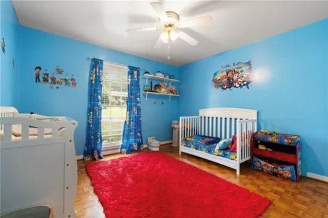 bedroom featuring ceiling fan, parquet floors, and a nursery area