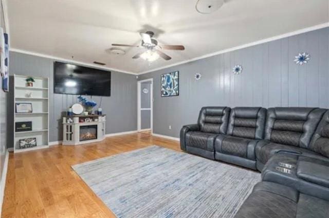 home theater with ceiling fan, wooden walls, crown molding, wood-type flooring, and a fireplace