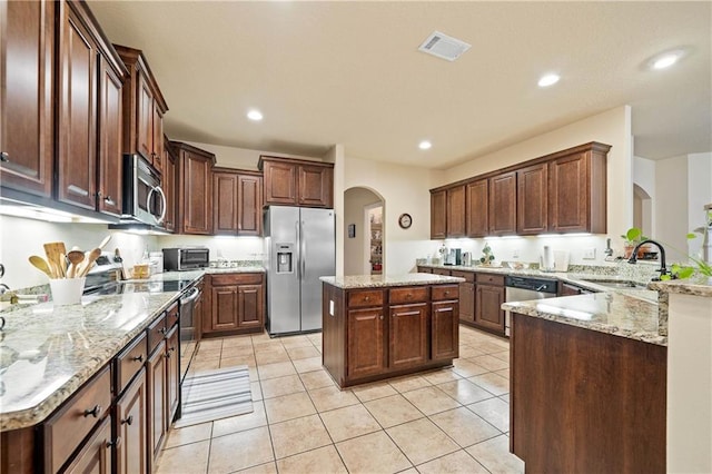 kitchen with light tile patterned flooring, sink, light stone countertops, a kitchen island, and stainless steel appliances