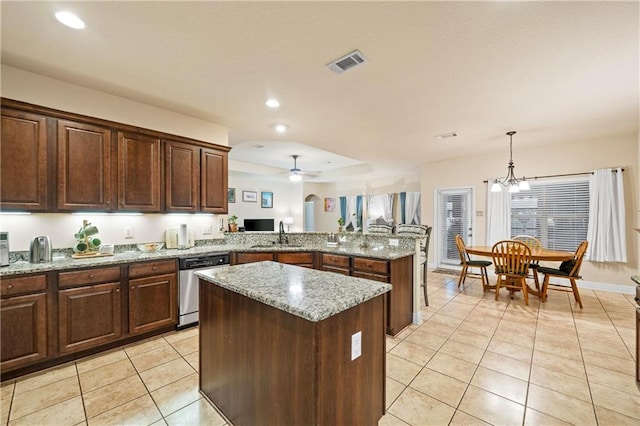 kitchen featuring light stone counters, stainless steel dishwasher, decorative light fixtures, a kitchen island, and ceiling fan with notable chandelier