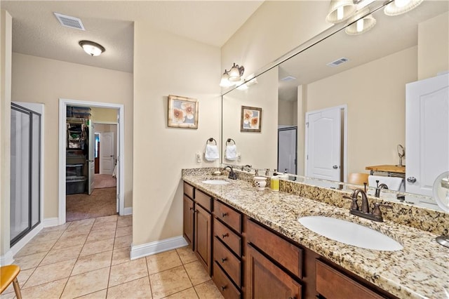 bathroom with a textured ceiling, vanity, tile patterned floors, and an enclosed shower