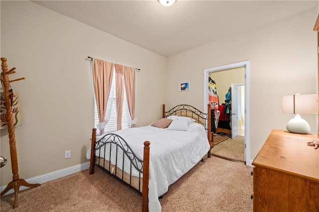 bedroom with light carpet, a textured ceiling, and a spacious closet