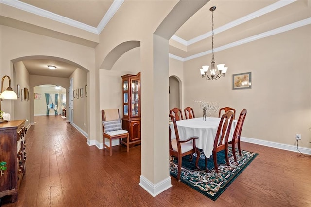 dining area with crown molding, dark hardwood / wood-style flooring, and an inviting chandelier