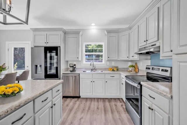 21621 Coleman Cemetery Rd, Moss Point, MS 39562 - kitchen featuring appliances with stainless steel finishes, a sink, under cabinet range hood, light wood finished floors, and crown molding