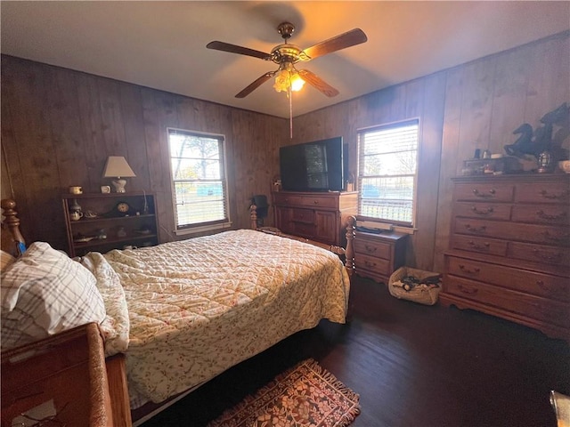 bedroom featuring ceiling fan, wooden walls, and multiple windows