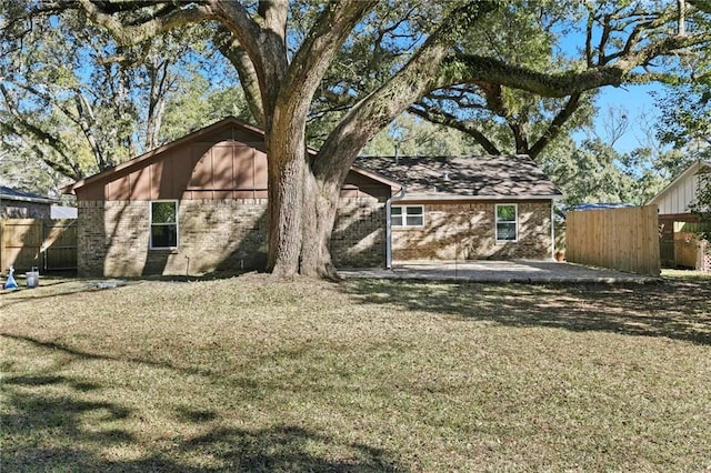 back of house with brick siding, a lawn, a patio area, and fence