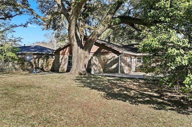 rear view of property with brick siding and a yard