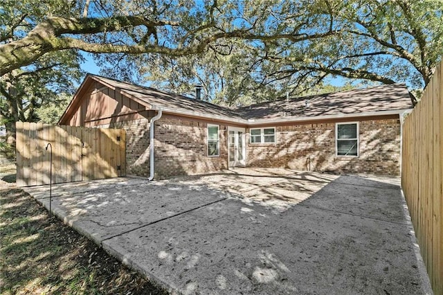 rear view of house with a patio area, brick siding, and fence