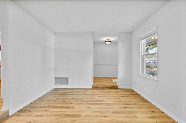 empty room featuring baseboards, visible vents, and wood finished floors