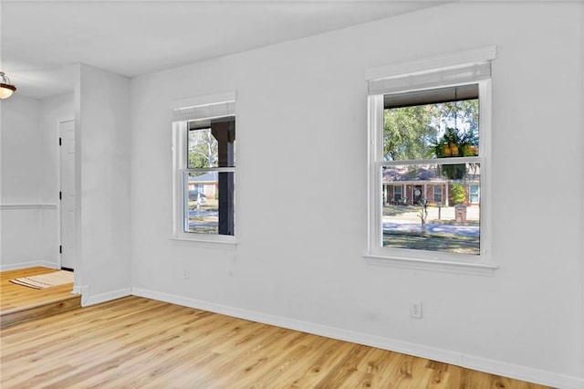 spare room featuring plenty of natural light, baseboards, and wood finished floors