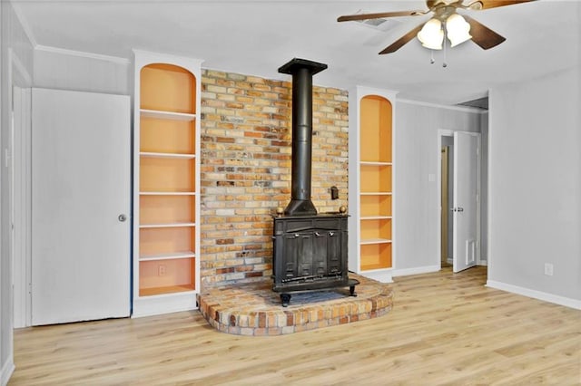 unfurnished living room with ornamental molding, a wood stove, built in features, and wood finished floors