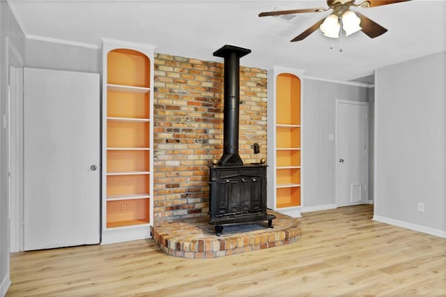 unfurnished living room with ornamental molding, a wood stove, built in shelves, and wood finished floors