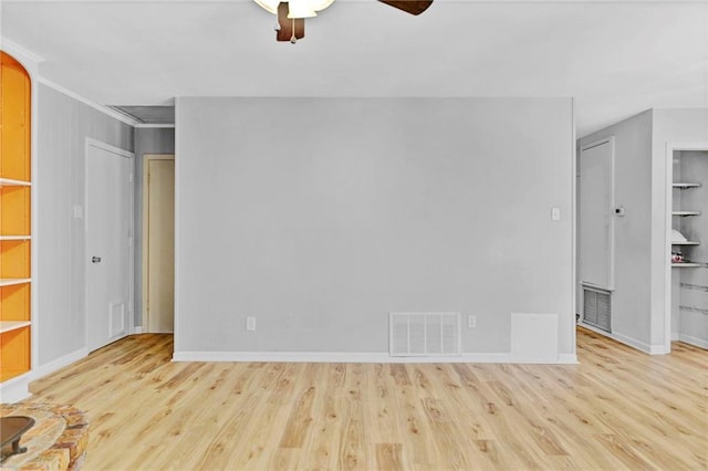 empty room with baseboards, wood finished floors, visible vents, and built in features