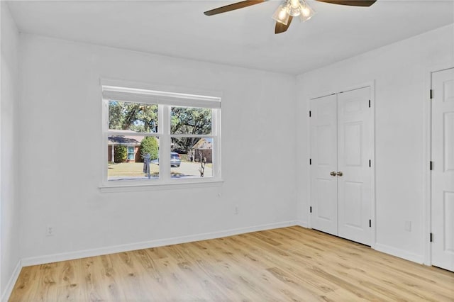 unfurnished bedroom with light wood-style floors, ceiling fan, and baseboards