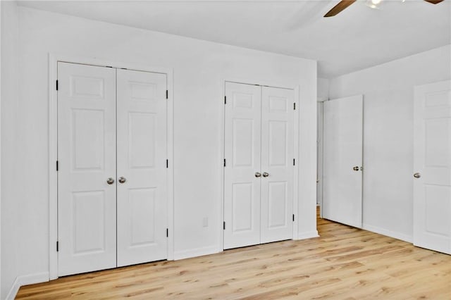 unfurnished bedroom with baseboards, light wood-style floors, and multiple closets