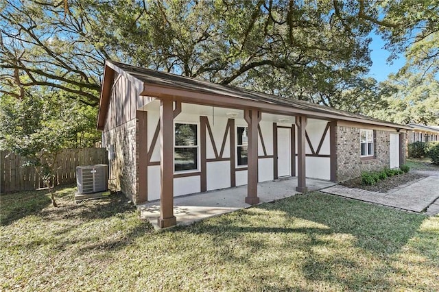 view of front of house featuring a front lawn, central AC unit, fence, and stucco siding