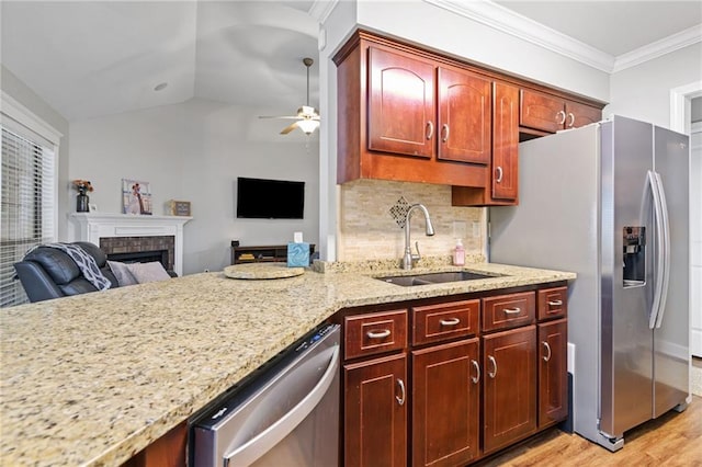 kitchen with a fireplace, crown molding, appliances with stainless steel finishes, a ceiling fan, and a sink