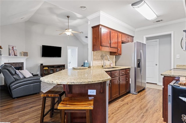 kitchen with open floor plan, a brick fireplace, a sink, and visible vents