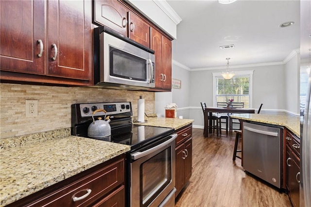 kitchen featuring light wood-style flooring, stainless steel appliances, visible vents, tasteful backsplash, and crown molding