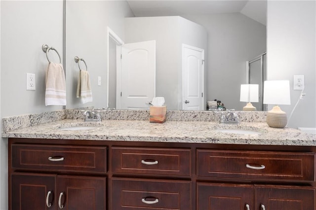 full bath with double vanity, vaulted ceiling, and a sink