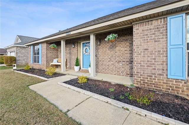 entrance to property with brick siding and a yard