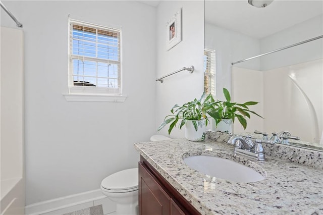 bathroom featuring toilet, a shower, vanity, and baseboards