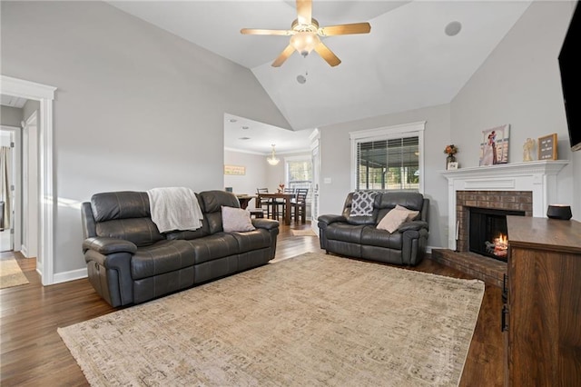 living room with dark wood finished floors, a ceiling fan, a brick fireplace, high vaulted ceiling, and baseboards