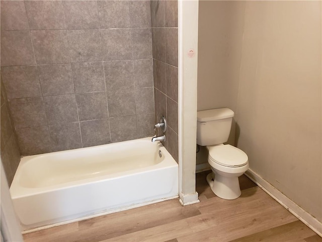 bathroom featuring hardwood / wood-style floors, toilet, and tiled shower / bath