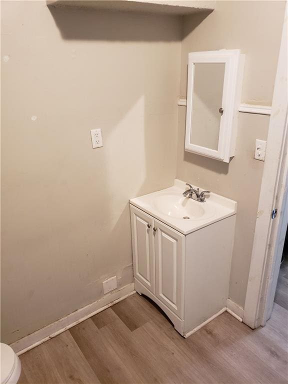 bathroom with hardwood / wood-style floors, vanity, and toilet