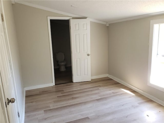 unfurnished bedroom with a textured ceiling, connected bathroom, light hardwood / wood-style flooring, and crown molding