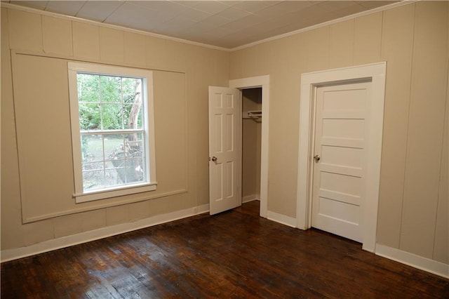 unfurnished bedroom with dark hardwood / wood-style flooring, ornamental molding, and a closet