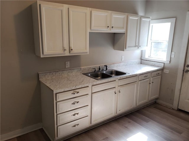 kitchen featuring light hardwood / wood-style floors, white cabinetry, and sink