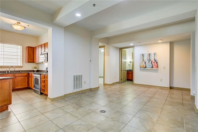 1430 Regency Rd Unit F204, Gulf Shores, AL 36542 - kitchen with stainless steel appliances, recessed lighting, light tile patterned floors, brown cabinets, and baseboards