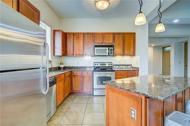 1430 Regency Rd Unit F204, Gulf Shores, AL 36542 - kitchen with appliances with stainless steel finishes, brown cabinetry, hanging light fixtures, light tile patterned floors, and dark stone countertops