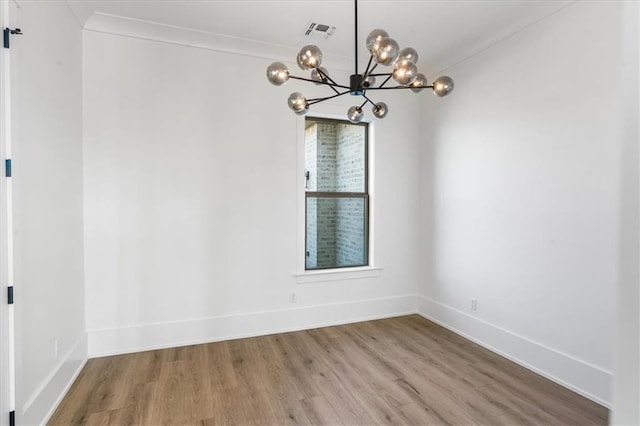 unfurnished dining area with wood-type flooring, a chandelier, and ornamental molding