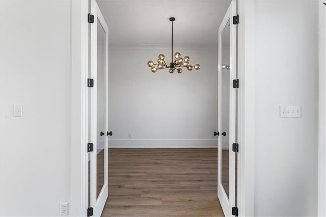 hallway with hardwood / wood-style flooring and a notable chandelier