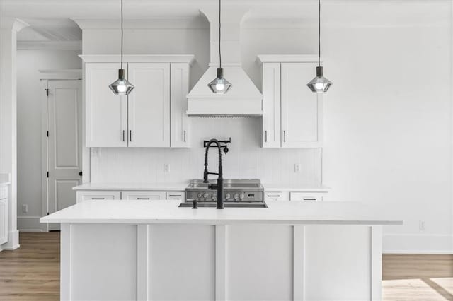 kitchen featuring white cabinetry, backsplash, light hardwood / wood-style floors, and hanging light fixtures