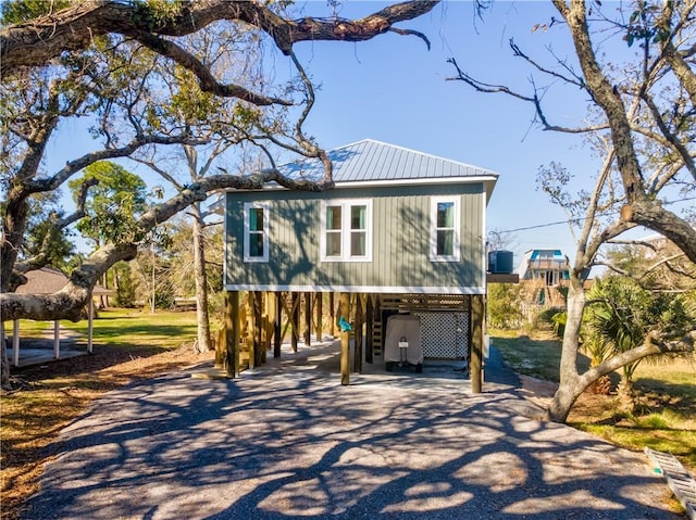 beach home featuring driveway, stairs, metal roof, and a carport