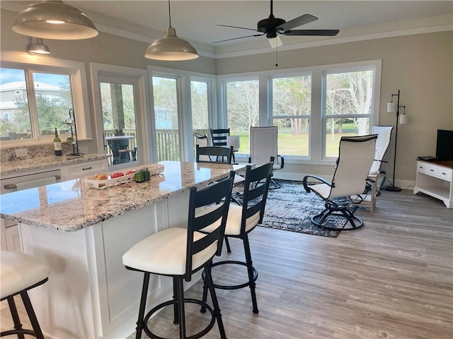 kitchen featuring ornamental molding, white cabinetry, light wood-style flooring, and a kitchen breakfast bar