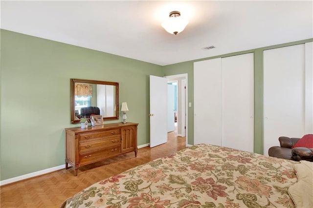 bedroom with baseboards, visible vents, and two closets