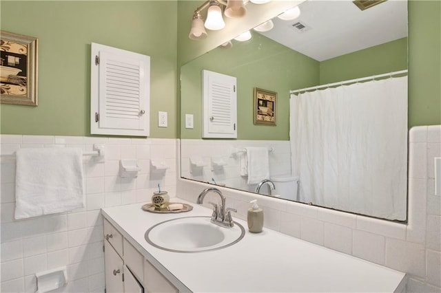 full bathroom with visible vents, tile walls, wainscoting, and vanity