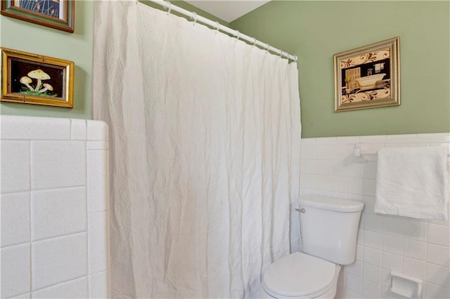 full bath featuring a wainscoted wall, toilet, tile walls, and a shower with shower curtain