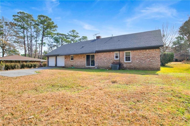 rear view of house with aphalt driveway, a yard, brick siding, and a garage