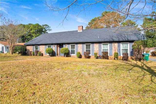 ranch-style home featuring roof with shingles, a chimney, and a front yard