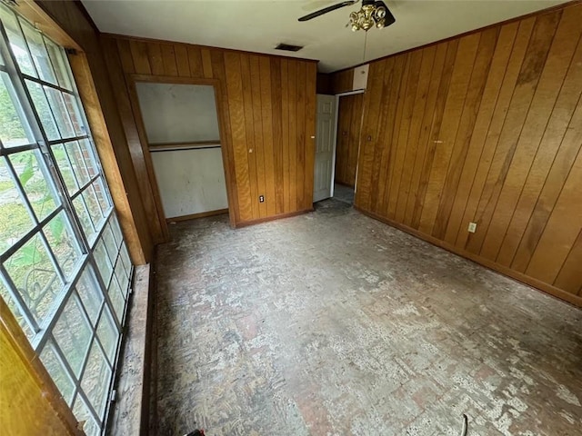 unfurnished bedroom with wood walls and ceiling fan