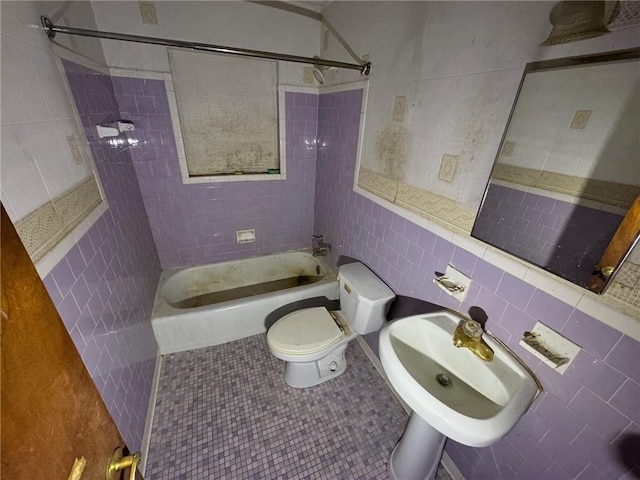 full bathroom featuring tile walls, toilet, tiled shower / bath combo, sink, and tile patterned floors