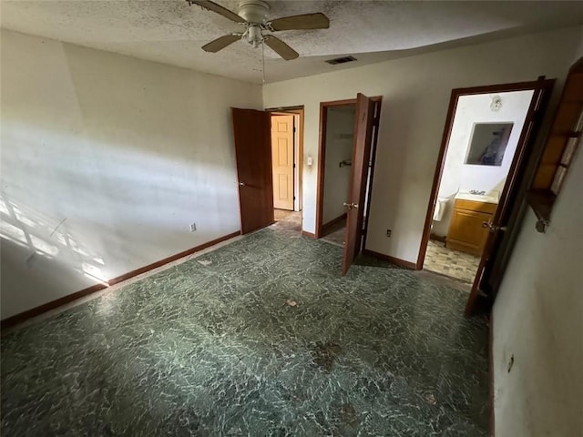 unfurnished bedroom with a textured ceiling, connected bathroom, and ceiling fan