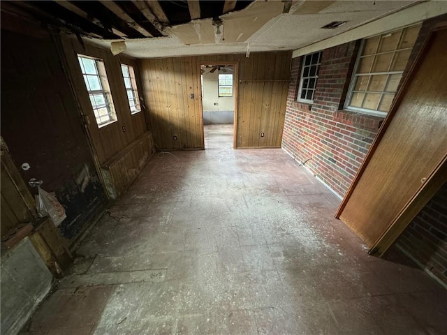 basement featuring wood walls and brick wall